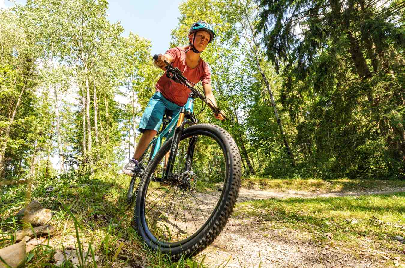 Chłopiec w kasku jadący na rowerze KUbikes MTB po leśnej ścieżce